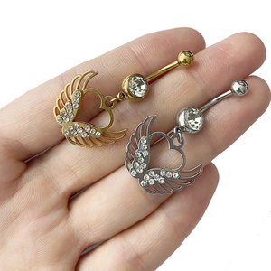 Détail macro de piercings de nombril ailes de cœur en or et argent avec cristaux