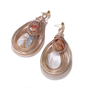 Macro detail of Bohemian teardrop earrings with gold wire wrap, amber gems and pearl inlay