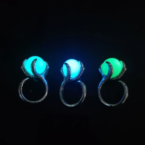 Detail of dragon claw rings with glowing beads in cyan, blue, and green on black background
