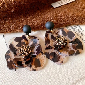 Detail view of leopard print acetate flower earrings with golden rose center and matte black stud