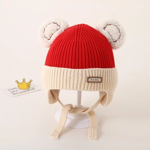 Red and white knit baby winter hat with two pom-poms and earflaps for wind protection