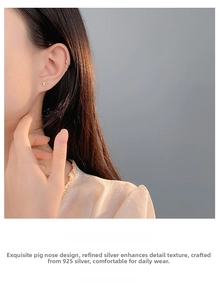 Close-up of golden 925 sterling silver pig nose stud earring worn on a female ear