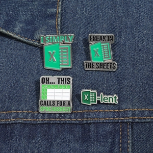 Detail of four green enamel spreadsheet pins with office humor on denim background