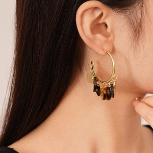 Detail of leopard resin sequins gold hoop earrings on model with layered pendants