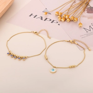 Detail of gold-plated evil eye anklet set with blue beads and crystal charm on beige background