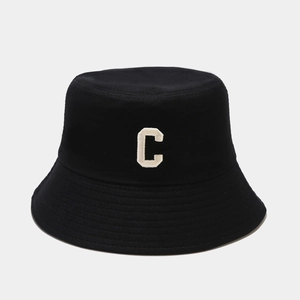 Détail d'un bob en coton avec une broderie épaisse de la lettre C en beige clair