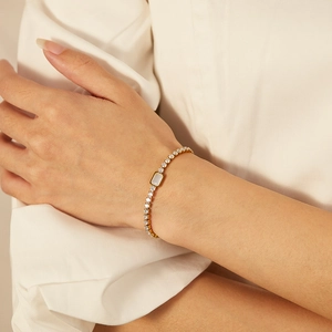 Elegant gold plated tennis bracelet with white crystals and rectangular stone on wrist