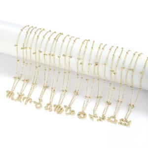 Detailed view of twelve gold-plated zodiac necklaces with cubic zirconia on white stands