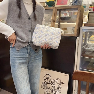 Détail d'une trousse de maquillage matelassée en coton blanc avec motifs ours et fleurs