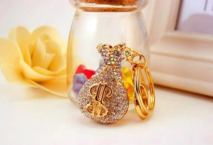 Close-up of golden crystal money bag keychain with rhinestones and dollar sign charm