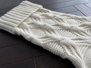 Macro shot of cream white knitted Christmas bag featuring intricate geometric diamond patterns
