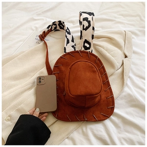 Detail of a brown suede backpack shaped like a cowboy hat with cow print wide shoulder straps
