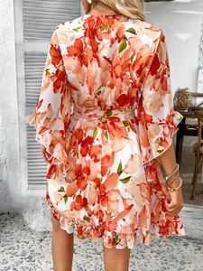 Detail view of orange floral chiffon dress showing the tie waist and flowy back design