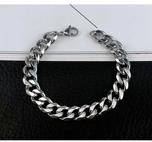 Detailed view of silver Cuban link bracelet with lobster clasp on leather background