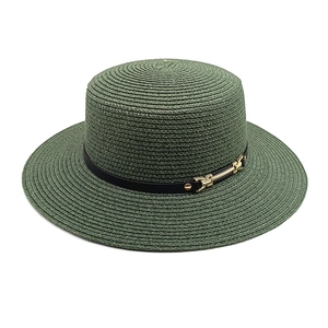 Détail du chapeau de paille vert foncé avec ruban noir et boucle dorée élégante