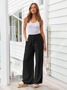 Detail of loose black wide-leg pants featuring a high-waisted drawstring and smooth drape