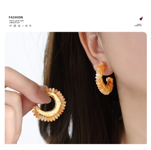 Detailed view of vintage gold C-shape hoop earrings with textured orange amber beads