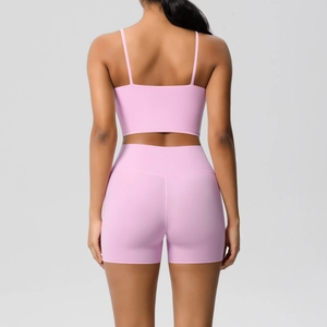 Detail of pink yoga set showing thin straps sports bra and high-waisted shorts on model