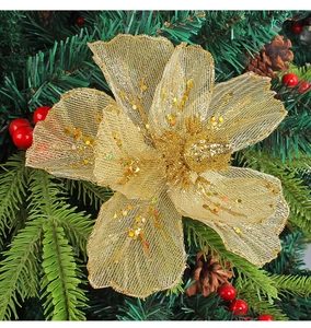 Detailed view of golden mesh Christmas flower with glitter sequins on green pine branches