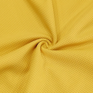 Primer plano del tejido de punto gofrado amarillo con textura 3D y caída suave