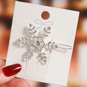 Close-up of sparkling snowflake hair clip with silver metal base and embedded rhinestones