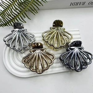 Shell-shaped metal hair claws in gold and silver finish on a stylish display stand