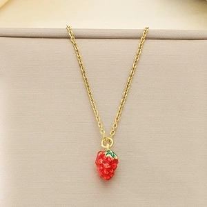 Detail of red strawberry pendant on golden stainless steel chain with realistic leaf texture