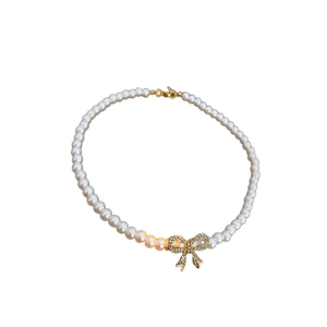Elegant white faux pearl necklace with sparkling rhinestone bow pendant on white background