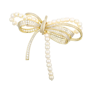 Elegant gold bow brooch with micro-set zircon and white pearls on a clean background