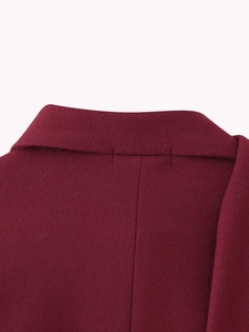Detailed stitching on the collar of this burgundy wool coat with a focus on texture