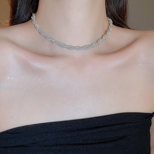 Detail view of silver twisted mesh necklace showing metallic texture on female model's collarbone