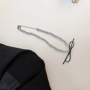 Elegant silver beaded necklace with a black ribbon bow pendant on a clean white backdrop
