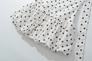 Detailansicht von weißem Chiffonstoff mit schwarzen Punkten und Rüschendesign