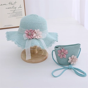 Détail d'un chapeau de paille bleu clair et d'un sac assorti avec fleurs en dentelle