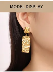 Close-up of golden geometric earrings with irregular lava texture on a model
