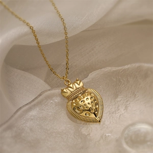 Detail of gold crown heart pendant with embossed texture on crystal-like surface