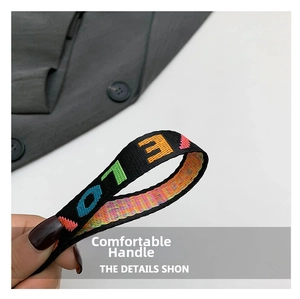 Détail d'une sangle en nylon noir avec des lettres brodées colorées sur le sac à main