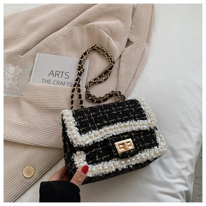Detailed macro view of black tweed bag featuring gold threads and white pearl trim