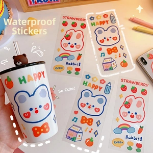 Close-up of cute strawberry bear PVC stickers on a water bottle and diary cover
