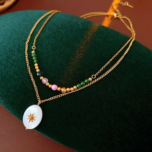 Detail of vintage layered necklace with colorful beads and gold sunburst oval pendant