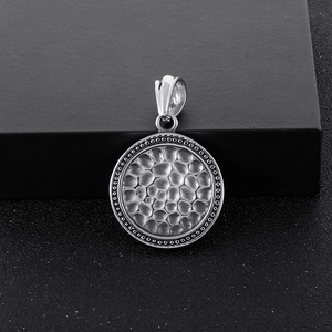 Close-up of vintage silver hammered texture round pendant with dotted edge on black box