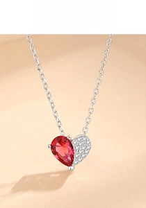 Close-up of heart necklace with red gemstone and white zircon pavé on silver chain