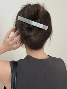 Détail d'une barrette rectangulaire en métal argenté brossé sur une coiffure relevée