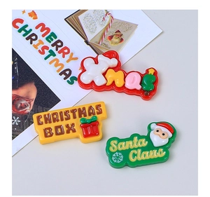 Nahaufnahme bunter Weihnachts-Resin-Charms mit Xmas- und Weihnachtsmann-Schriftzug