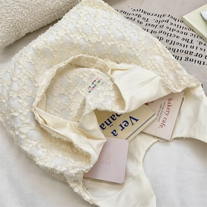 Close-up of cream white lace tote bag with textured floral jacquard and interior logo tag