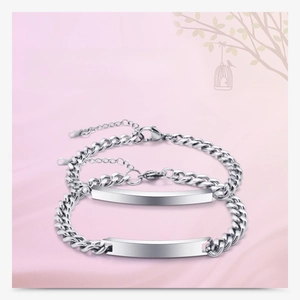 Close-up of dual silver stainless steel Cuban link ID bracelets with polished metal plates