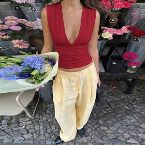 Dettaglio di un top a portafoglio bordeaux con scollo a V profondo e pantaloni in lino beige