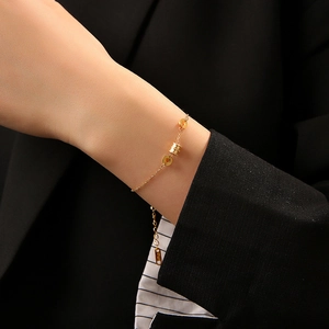 Élégant bracelet chaîne en or avec pendentif cylindrique porté sur un poignet