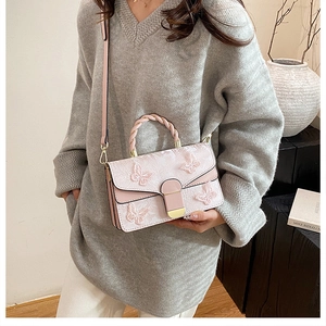 Détail du sac en dentelle rose avec papillons 3D et poignée supérieure tressée élégante