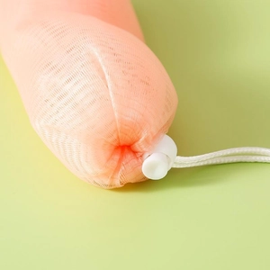 Detail of orange mesh soap foaming bag with drawstring and plastic cord lock